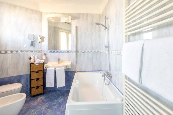 Badezimmer im Baia Imperiale Hotel mit Badewanne, Waschbecken und Dusche.