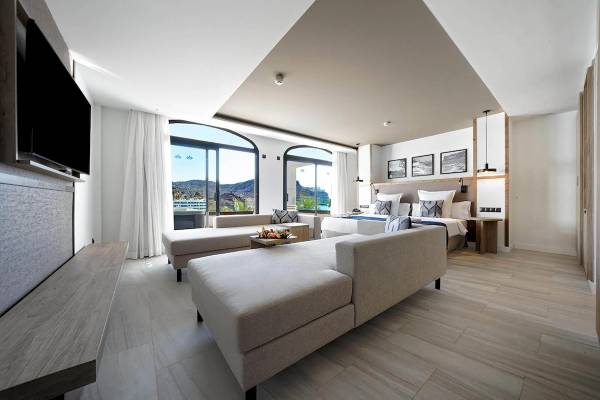 Innenansicht des Schlafzimmers im H10 Costa Mogan Hotel mit Bett, Couch, Fernseher und Fenster