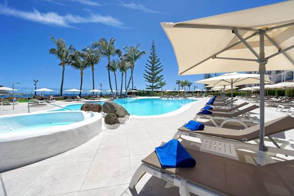 Poolbereich des H10 Costa Mogan Hotels mit Liegen und Sonnenschirmen