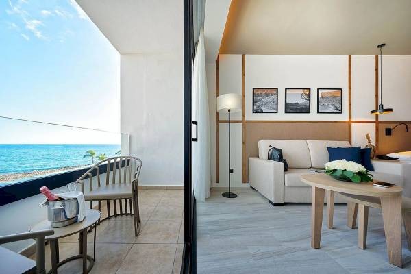 Suite im H10 Costa Mogan mit Meerblick, inklusive Sofa, Tisch und Balkon mit Blick auf das Meer.