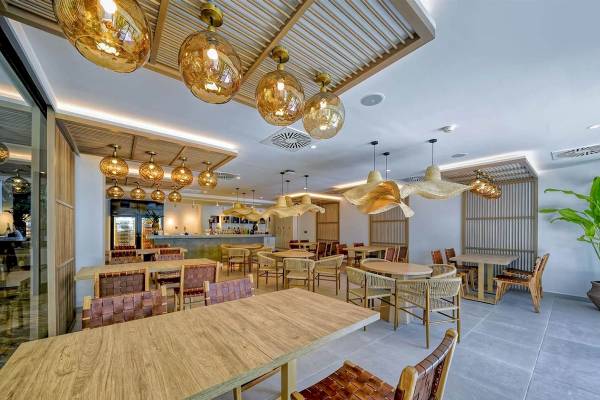 Innenbereich des Restaurants im H10 Costa Mogan Hotel mit modernen Holztischen und Stühlen.