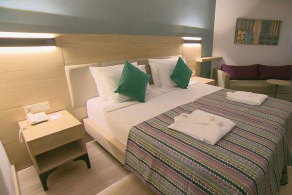 Doppelbett-Zimmer im Belek Beach Resort Hotel mit grün und weißen Kissen und einem Tischtelefon.