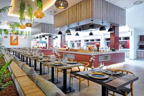 Innenbereich des H10 Costa Mogan Hotels mit Tisch, Stühlen und Speisenbuffet.