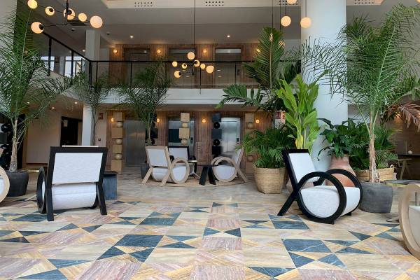 Lobby des H10 Costa Mogan Hotels mit moderner Einrichtung und vielen Pflanzen.