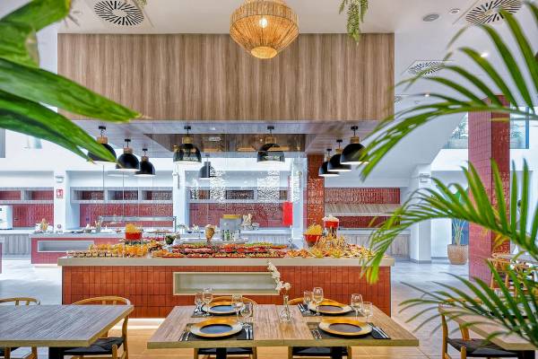 Innenansicht des Restaurants im H10 Costa Mogan Hotel mit Buffet, Tischen und Stühlen.