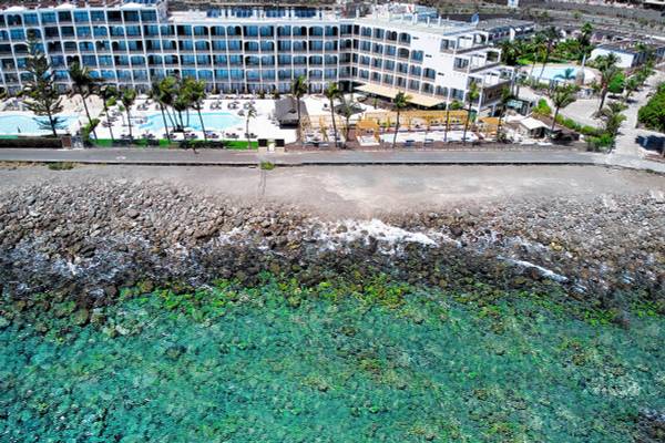Luftaufnahme des H10 Costa Mogan Hotels mit Swimmingpools und Blick auf das Meer.