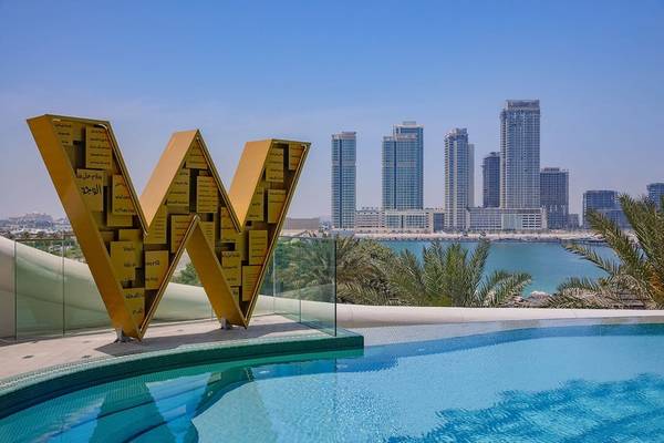 Außenpool mit W-Logo und Blick auf die Skyline von Dubai im Mina Seyahi Hotel.