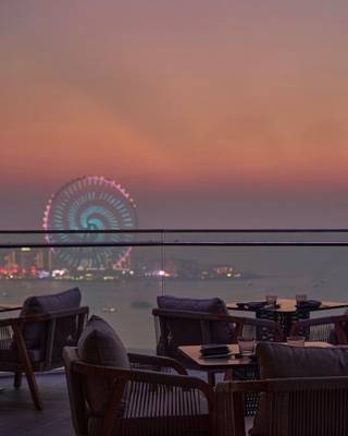Abendliche Terrasse des W Dubai - Mina Seyahi mit Blick auf eine Stadt und ein Riesenrad