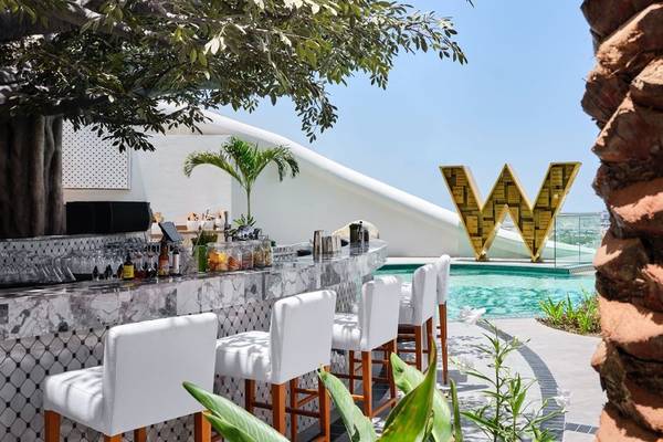 Bar am Pool des W Dubai - Mina Seyahi Hotels mit weißen Stühlen und großer W-Letter.