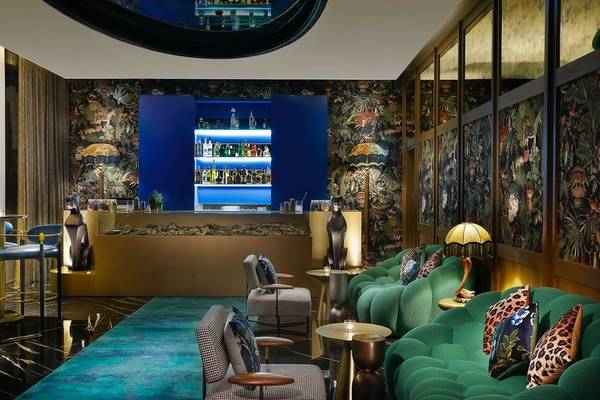 Innenraum des W Dubai - Mina Seyahi Hotels mit grünen Sofas, blauem Teppich und einer Bar.