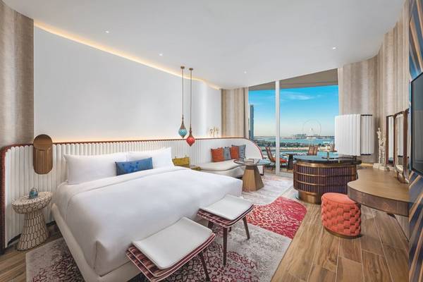 Innenansicht des Schlafzimmers im W Dubai - Mina Seyahi Hotel mit großem Bett, Blick auf die Stadt und Wasser.