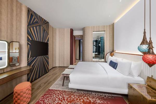 Innenansicht des Schlafzimmers im W Dubai - Mina Seyahi Hotel mit großem Bett und moderner Einrichtung.