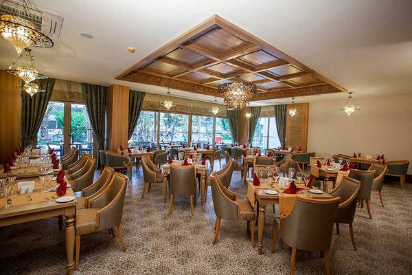 Restaurant im Belek Beach Resort Hotel mit gedeckten Tischen und hängenden Kronleuchtern.