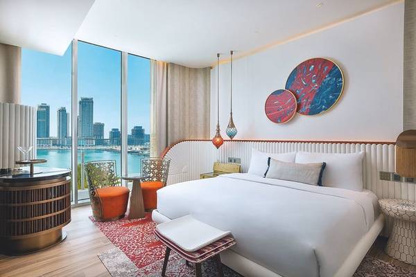 Innenansicht eines Zimmers im W Dubai - Mina Seyahi Hotel mit großem Bett und Blick auf die Stadt.