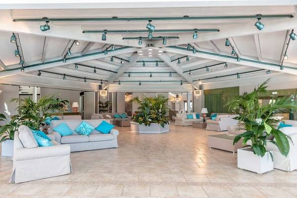 Hotellobby von Acacia Marina mit vielen Sofas, Pflanzen und Lampen an der Decke.