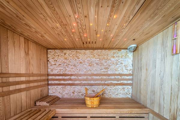 Eine Holzsauna mit einem Holzbecken und einer beleuchteten Decke.