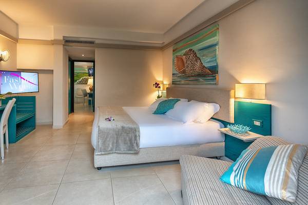 Hotelzimmer im Acacia Marina mit einem großen Bett, einer Couch und blauen Möbeln.