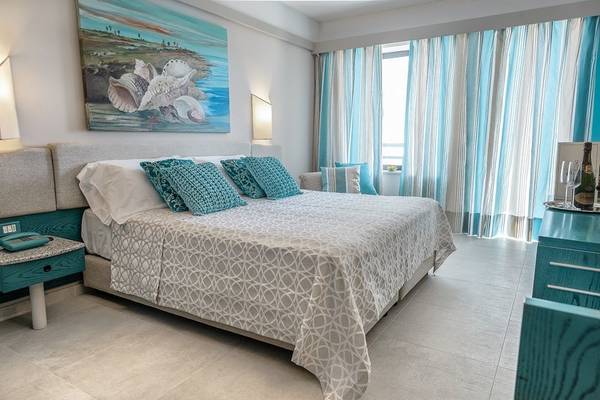 Schlafzimmer im Acacia Marina Hotel mit einem großen Bett und blauen Kissen.