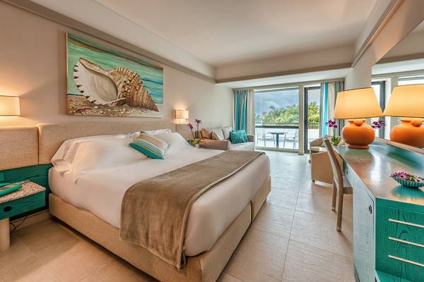 Schlafzimmer im Acacia Marina Hotel mit großem Bett und Meeresmuschel-Kunstwerk.