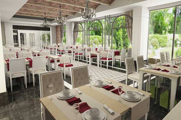Innenansicht des Restaurants im Belek Beach Resort Hotel mit vielen Tischen und Stühlen, hängenden Kronleuchtern und großen Fenstern.