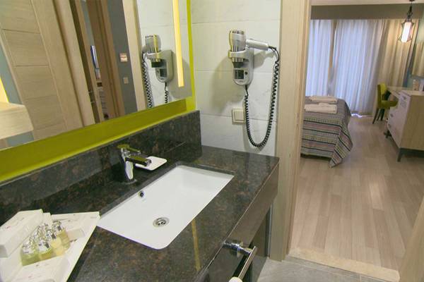 Ein Badezimmer des Belek Beach Resort Hotels mit einem Waschbecken, Spiegel und Haartrockner.