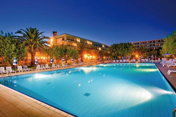 Außenpool des UNAHOTELS Naxos Beach Sicilia bei Nacht mit vielen Liegen und Sonnenschirmen.