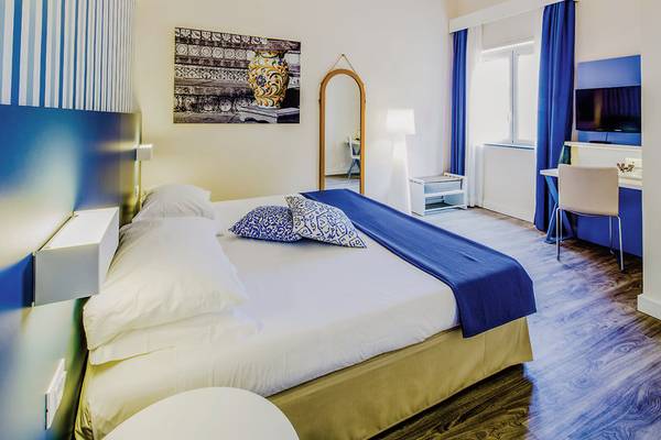 Ein stilvolles Hotelzimmer im UNAHOTELS Naxos Beach Sicilia mit einem bequemen Bett, Dekor und Einrichtung.