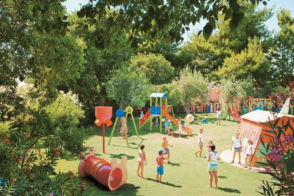 Kinderspielplatz im Freien im UNAHOTELS Naxos Beach Sicilia mit verschiedenen Spielgeräten und Kindern, die spielen.