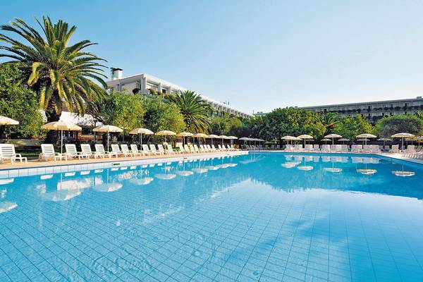 Ein großer Swimmingpool mit weißen Liegestühlen und Sonnenschirmen im Freien des UNAHOTELS Naxos Beach Sicilia.