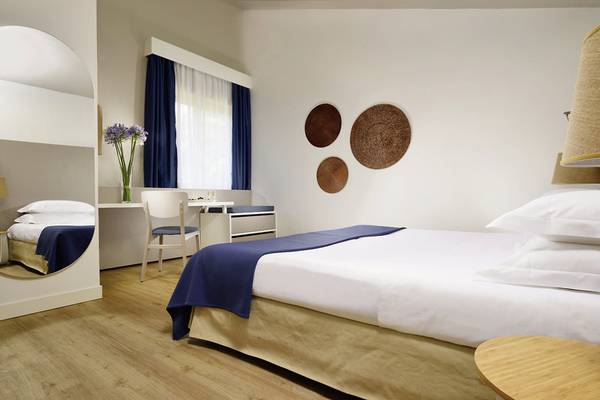 Hotelzimmer im UNAHOTELS Naxos Beach Sicilia mit Bett, Schreibtisch und Dekoartikeln.