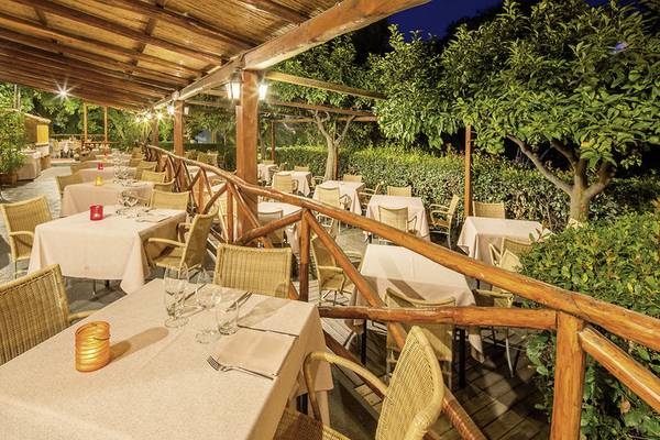 UNAHOTELS Naxos Beach Sicilia Terrasse bei Nacht mit gedeckten Tischen und brennenden Kerzen.