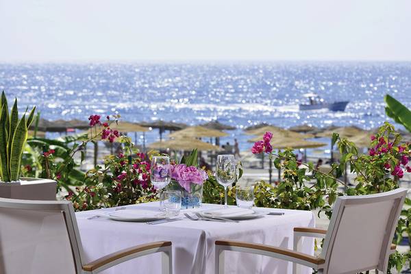 Tisch am Strand im Hotel UNAHOTELS Naxos Beach Sicilia mit Blick auf das Meer und Sonnenschirme.