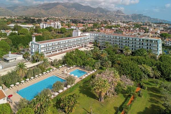 Außenansicht des UNAHOTELS Naxos Beach Sicilia mit Swimmingpool und Palmen