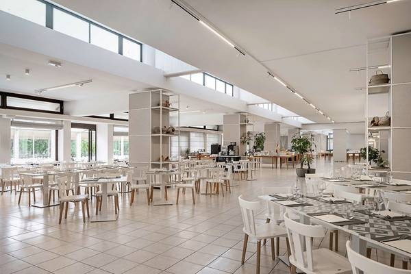 Innenansicht des Restaurants im UNAHOTELS Naxos Beach Sicilia mit weißen Tischen und Stühlen.