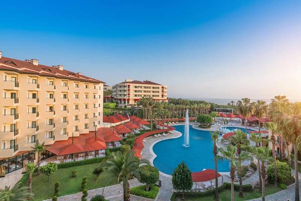 Außenansicht des Miramare Queen Hotels mit Swimmingpool, Sonnenschirmen und Palmen