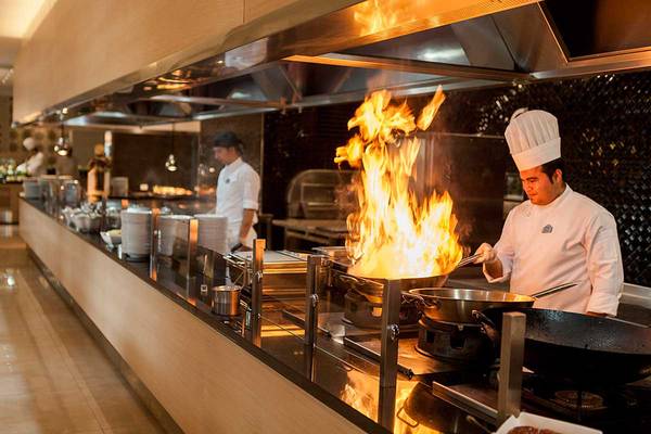Koch im Hotelrestaurant, der mit Feuer brät