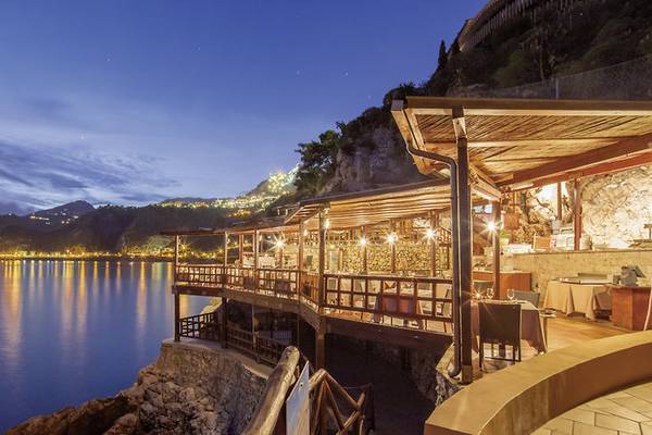 Terrasse des UNAHOTELS Capotaormina bei Nacht mit Blick auf den Berg und das Meer.
