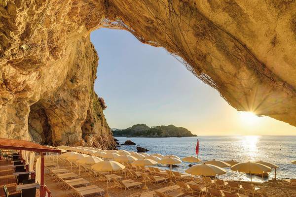 Sonnenuntergang am Strand des UNAHOTELS Capotaormina mit vielen Sonnenschirmen und Liegen