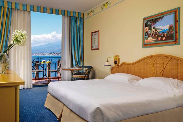 Hotelzimmer mit Meerblick bei UNAHOTELS Capotaormina, mit einem großen Bett, Balkon und Aussicht auf das Meer.