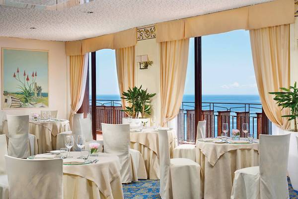Hotelrestaurant mit Blick auf das Meer und Pflanzendekorationen.