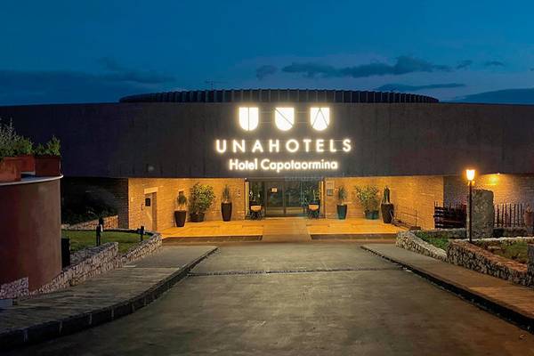 Haupteingang des UNAHOTELS Capotaormina bei Nachtbeleuchtung, Logo und Name sichtbar