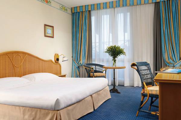 Hotelzimmer im UNAHOTELS Capotaormina mit Doppelbett, Tisch, Stühlen und Fenstern
