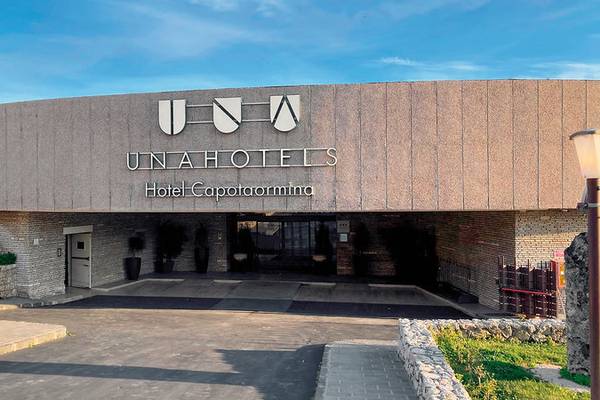 UNAHOTELS Capotaormina Hoteleingang mit Logo und modernen Architekturelementen.
