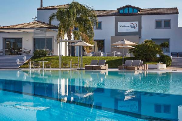 Außenbereich des VOI Marsa Siclà Essentia Resorts mit Swimmingpool, Sonnenliegen und Sonnenschirmen.