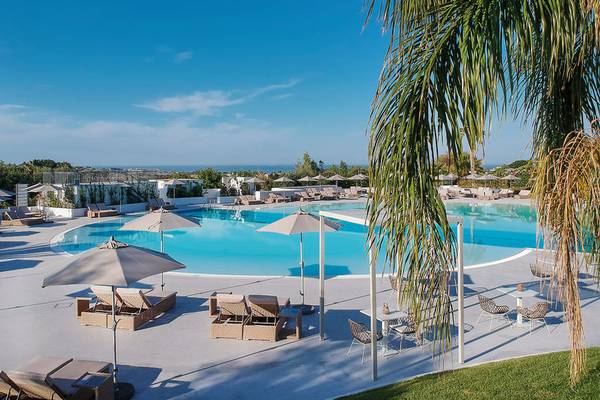 Außenpoolbereich des VOI Marsa Siclà Essentia Hotels mit Sonnenliegen und Sonnenschirmen.