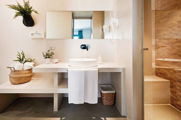 Badezimmer im VOI Marsa Siclà Essentia mit weißem Waschtisch, Handtüchern und Pflanzen.