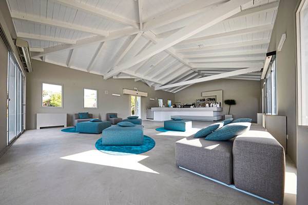 Lounge-Bereich des VOI Marsa Siclà Essentia Hotels mit grauen Sofas, blauen Kissen und weißer Decke.