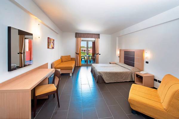 Innenansicht eines Hotelzimmers im VOI Baia di Tindari Resort mit Bett, Schreibtisch und Balkon