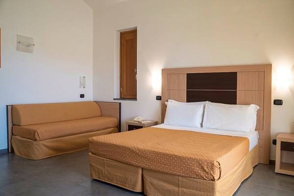 Schlafzimmer im VOI Baia di Tindari Resort mit Bett, Sofa und Nachttisch.