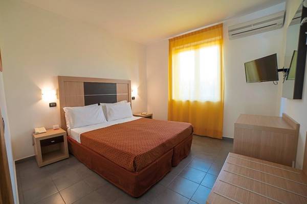 Ein ruhiges Zimmer im VOI Baia di Tindari Resort mit Doppelbett, Nachttischen und Fernseher.